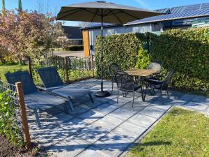 eine Terrasse mit einem Tisch, Stühlen und einem Sonnenschirm in der Unterkunft 't Hok in Hollum