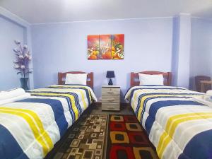 a bedroom with two beds and a painting on the wall at Samay Wasi - Aeropuerto in Lima