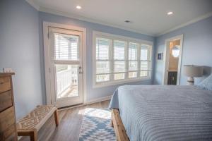 a bedroom with blue walls and a bed and windows at Three Girls in Holden Beach