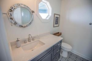 a bathroom with a sink and a mirror and a toilet at Three Girls in Holden Beach