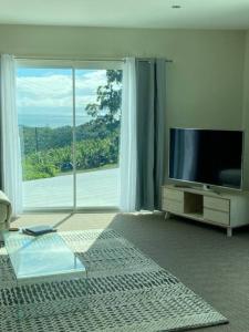 a living room with a television and a large window at Ocean View Oasis, Coffs Harbour in Coffs Harbour