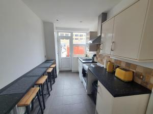 a large kitchen with black counter tops and tables at One Bed Apartment With Sofa Bed in Llandudno