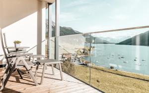 een balkon met stoelen en uitzicht op een waterlichaam bij Seehotel Panorama Relax in Resia