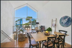 a dining room with a table and chairs and a large window at Lonnie Beach View Apartment in Point Lonsdale