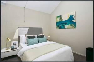 - une chambre avec un lit et une peinture murale dans l'établissement Lonnie Beach View Apartment, à Point Lonsdale