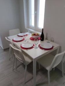 - une table blanche avec des assiettes rouges et une bouteille de vin dans l'établissement Sea U, à La Canée