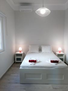 a white bedroom with a white bed with two red candles on it at Sea U in Chania