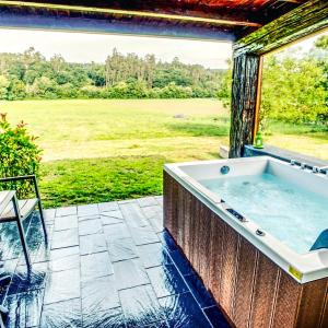 a hot tub on a patio with a view of a field at A Carballeira do Tambre in Troitosende