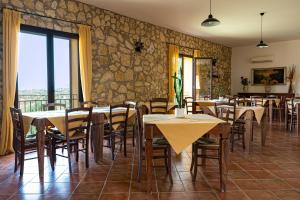 a restaurant with tables and chairs and a stone wall at Casale Ginisara in Castellammare del Golfo