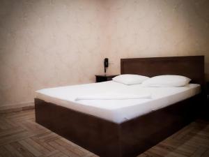 Green Garden Hotel في يريفان: سرير كبير بملاءات ووسائد بيضاء