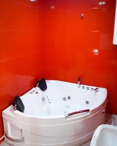 Green Garden Hotel في يريفان: حوض استحمام في الحمام بجدران برتقالية