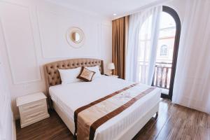 a white bedroom with a large bed and a window at Golden Sea Hotel in Ha Long