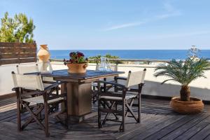 einen Holztisch und Stühle auf einer Terrasse mit Strand in der Unterkunft Kreta Natur in Hersonissos
