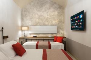 a bedroom with two beds and a tv on the wall at Dimora del Leone Gaeta in Gaeta