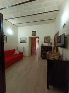 マテーラにあるCasa Vacanze Cosmaのウッドフロアのリビングルーム(赤いソファ付)