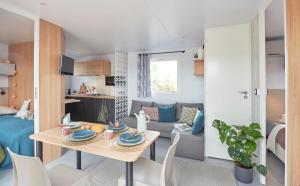 a room with a dining table and a living room at Camping Le Panoramic in Binic