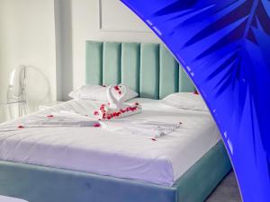 a bed with a blue headboard and white sheets and decorations at Mucobega Hotel 2 in Sarandë