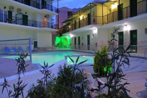 una piscina frente a dos edificios por la noche en Vergina Star Hotel en Nikiana