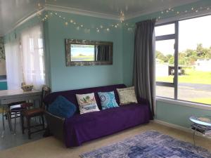 a living room with a purple couch and a table at Beach Belle in Bowentown