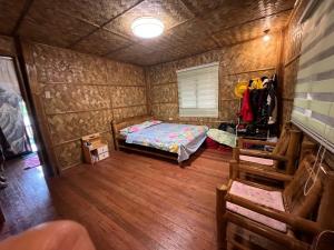 um pequeno quarto com uma cama e piso em madeira em Bahay Kubo ZaiLaiH em Silang