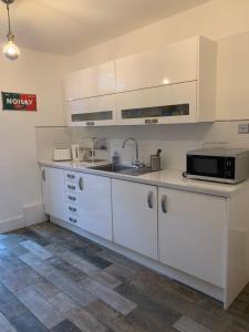 a kitchen with white cabinets and a sink and a microwave at The Courtyard in Wells