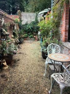 einen Garten mit einem Tisch, Stühlen und Topfpflanzen in der Unterkunft The Courtyard in Wells