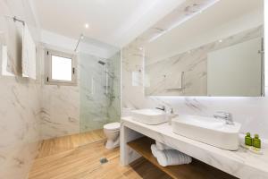 uma casa de banho branca com 2 lavatórios e um WC em Senses Suites em Dassia