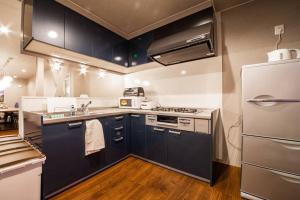 - une cuisine avec des armoires noires et un réfrigérateur blanc dans l'établissement THE SUN LOUNGE, à Kushiro