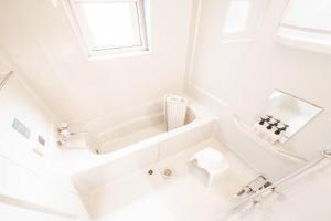 a white bathroom with a tub and a sink at THE BEEHIVEⅠ in Sapporo