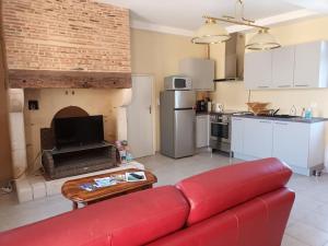 a living room with a red couch and a kitchen at GÎTE AUX BOIS D'EN TEMPS in Lunas +26 photos