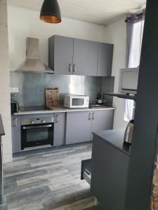 uma cozinha com armários brancos e um forno com placa de fogão em Bienvenue chez les ch'oups 50m2 terrasse 30m2 em La Bourboule
