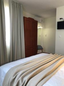 Iolkos Hotel Apartments في كاتو داراتسو: غرفة نوم بسرير وخزانة خشبية