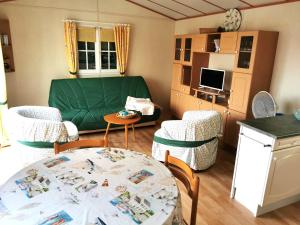 ein Wohnzimmer mit einem grünen Sofa und einem Tisch in der Unterkunft Mobil Home L'Evasion in Brem Sur Mer