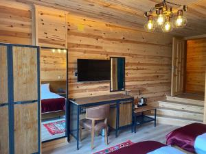 a log cabin bedroom with a desk and a tv at Yamacda Suit Otel in Çamlıhemşin