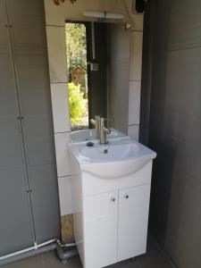 La salle de bains est pourvue d'un lavabo blanc et d'un miroir. dans l'établissement Gite Atypique Caravane Vintage et piscine ouverte du 15 Mai au 30 Septembre, à Godinne