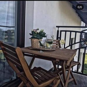 une table en bois avec des verres à vin et une plante sur un balcon dans l'établissement Morska Ostoja Chłapowo, à Władysławowo