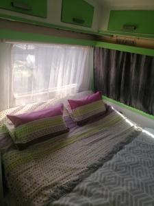 a bed with three pillows on top of it at Gite Atypique Caravane Vintage et piscine ouverte du 15 Mai au 30 Septembre in Godinne