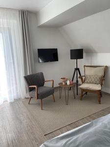Hotel Alte Mühle في باد بيتريتش: غرفة نوم مع كرسيين وتلفزيون على الحائط