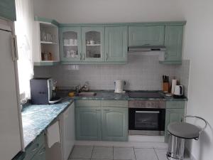 una cocina con armarios verdes y fregadero en Blue House en Győrzámoly