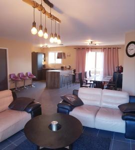 una sala de estar con sofás blancos y una mesa. en Grande maison près de Bordeaux Parking Pétanque WiFi en Beychac-et-Caillau