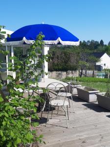 a table and chairs and an umbrella on a patio at Les écureuils bourguignons in Montchanin
