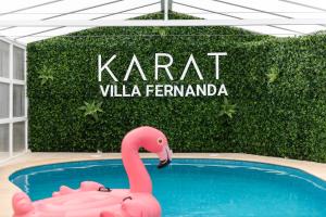 Un flamenco rosado en una piscina frente a un cartel. en KARAT Villa Fernanda, en Tacoronte