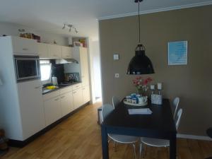 een keuken en eetkamer met een zwarte tafel en stoelen bij De Boomhut in Buren