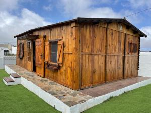 ein Holzgebäude mit Türen und Fenstern auf dem Rasen in der Unterkunft Agradable Mini Casa de madera con jardín amplio in La Laguna