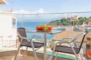 a table with a bowl of fruit on a balcony at Limani Apartments in Kassiopi