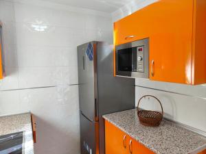 a small kitchen with orange cabinets and a microwave at Casa Flori in Celorio