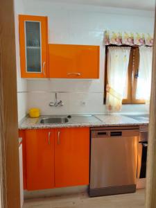 eine Küche mit orangefarbenen Schränken und einem Waschbecken in der Unterkunft Casa Flori in Celorio