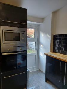 a kitchen with a microwave oven and a window at Apartment & Rooms in London in Croydon