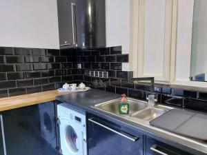 a kitchen with a washing machine and a sink at Apartment & Rooms in London in Croydon