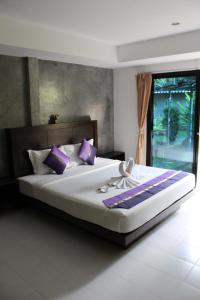 ein Schlafzimmer mit einem großen Bett mit lila Kissen in der Unterkunft B Happy Resort - SHA ExtraPlus in Kamala Beach + 37 Fotos